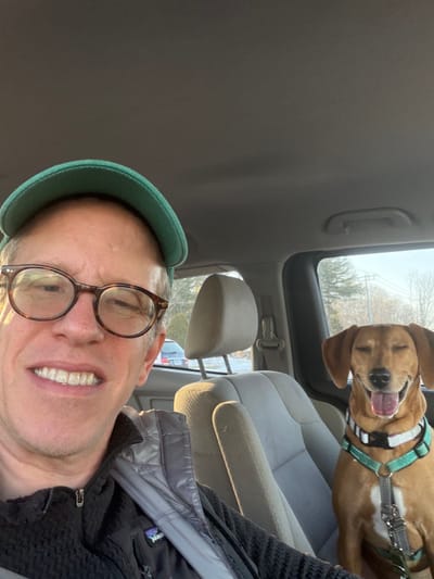 a man and his pet hound sit in a minivan en route to the beach
