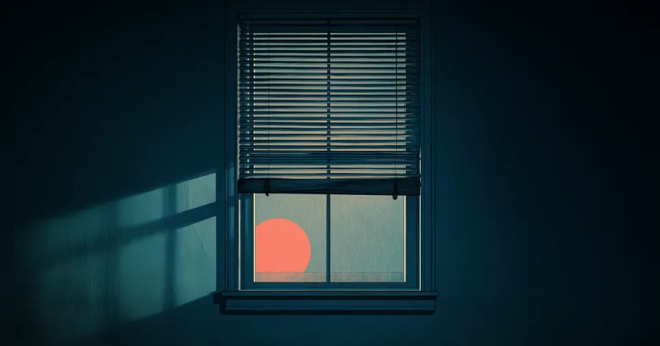 Window blinds in a dark room, halfway down, with a setting sun visible. 