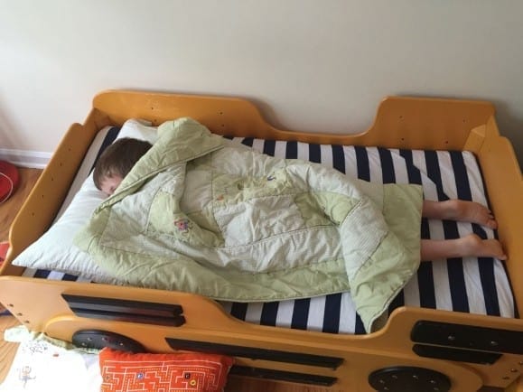 Child in school bus toddler bed that is too small for him