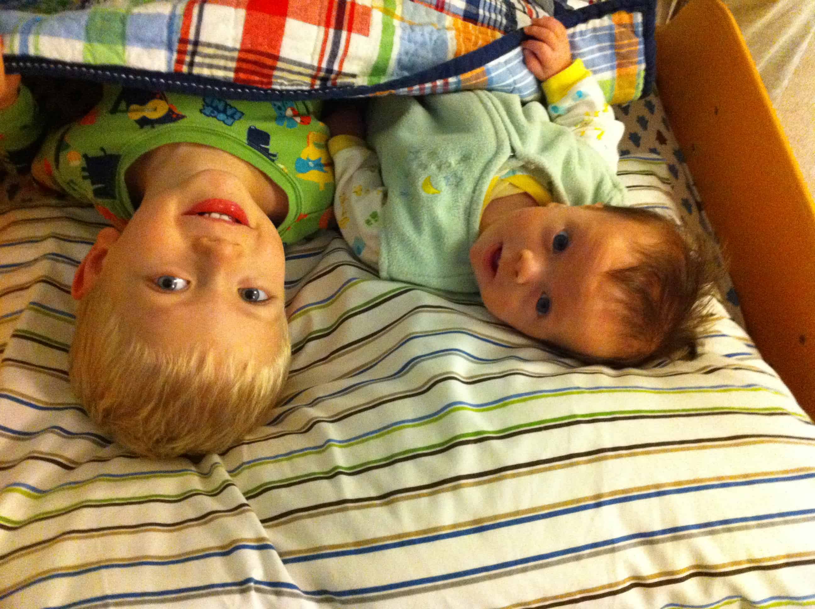 Two boys smiling in a toddler bed